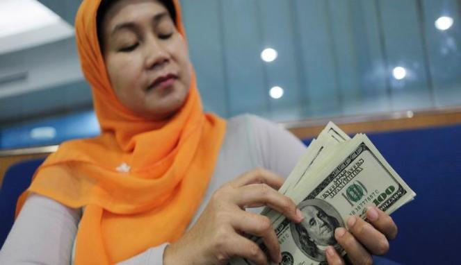 Seorang perempuan menghitung uang kertas dolar AS